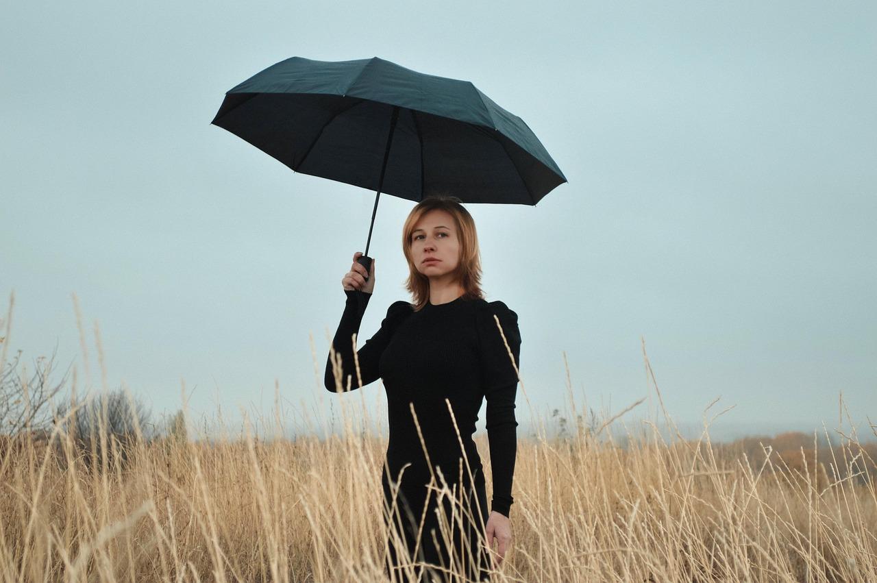 Vrouw met regenscherm in dor landschap