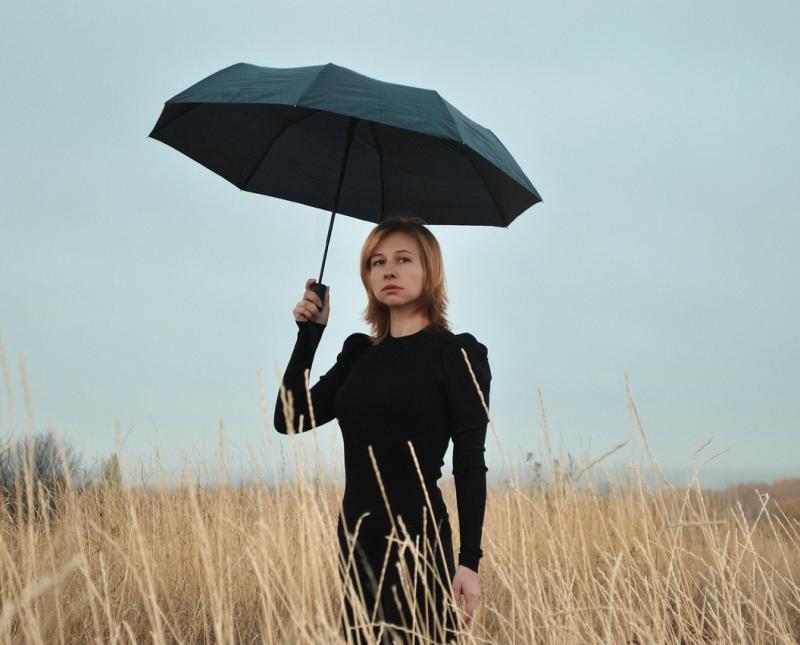 Vrouw met regenscherm in dor landschap