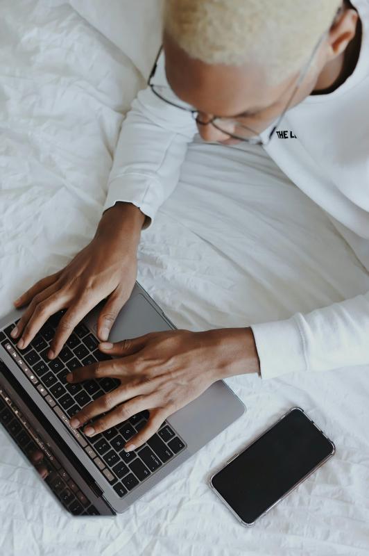 man typt op laptop, foto is van bovenaf getrokken