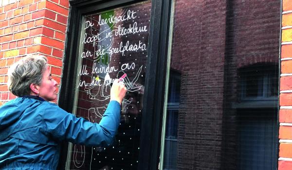 Stadsdichter Liesbeth Aerts brengt een weesgedicht aan op een raam