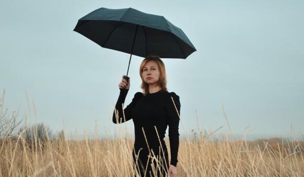 Vrouw met regenscherm in dor landschap